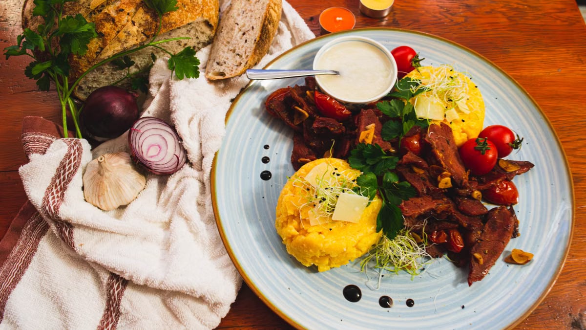 Delicious Romanian cuisine featuring polenta, vegetables, and artisan bread in a vibrant setting.