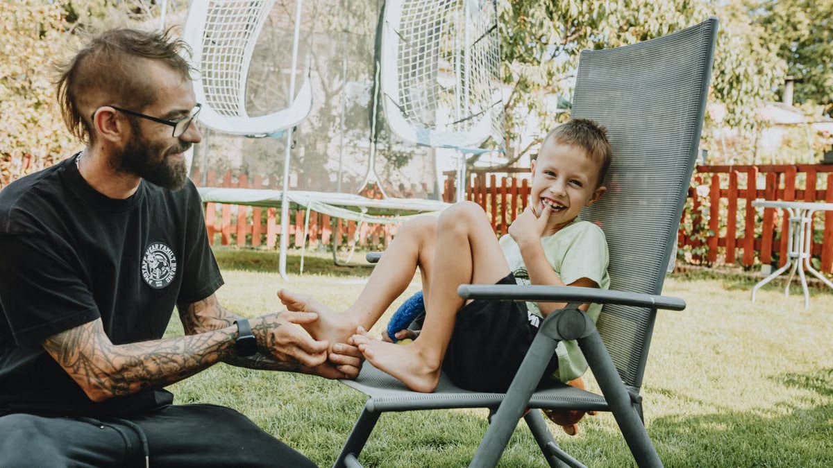 Playful interaction between a father and son in a sunny backyard setting.